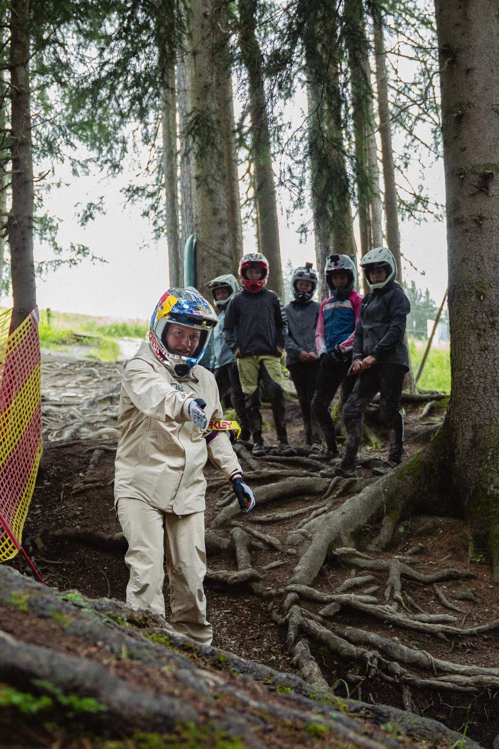 Gruppe Sportler mit Helmen im Wald mit Baumwurzeln.