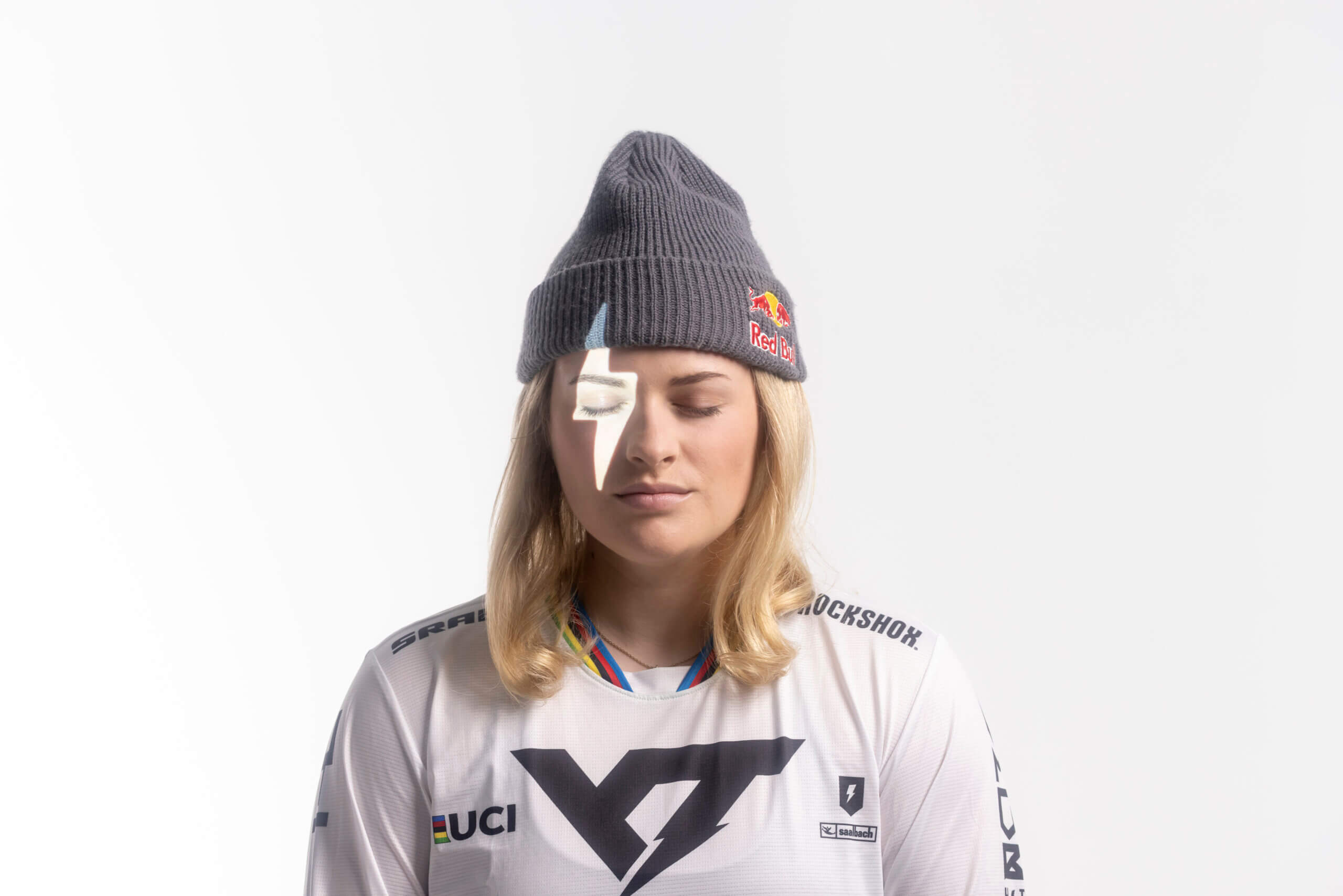 Blonde Frau mit Mütze, geschlossenen Augen, weißer Blitz auf Gesicht.