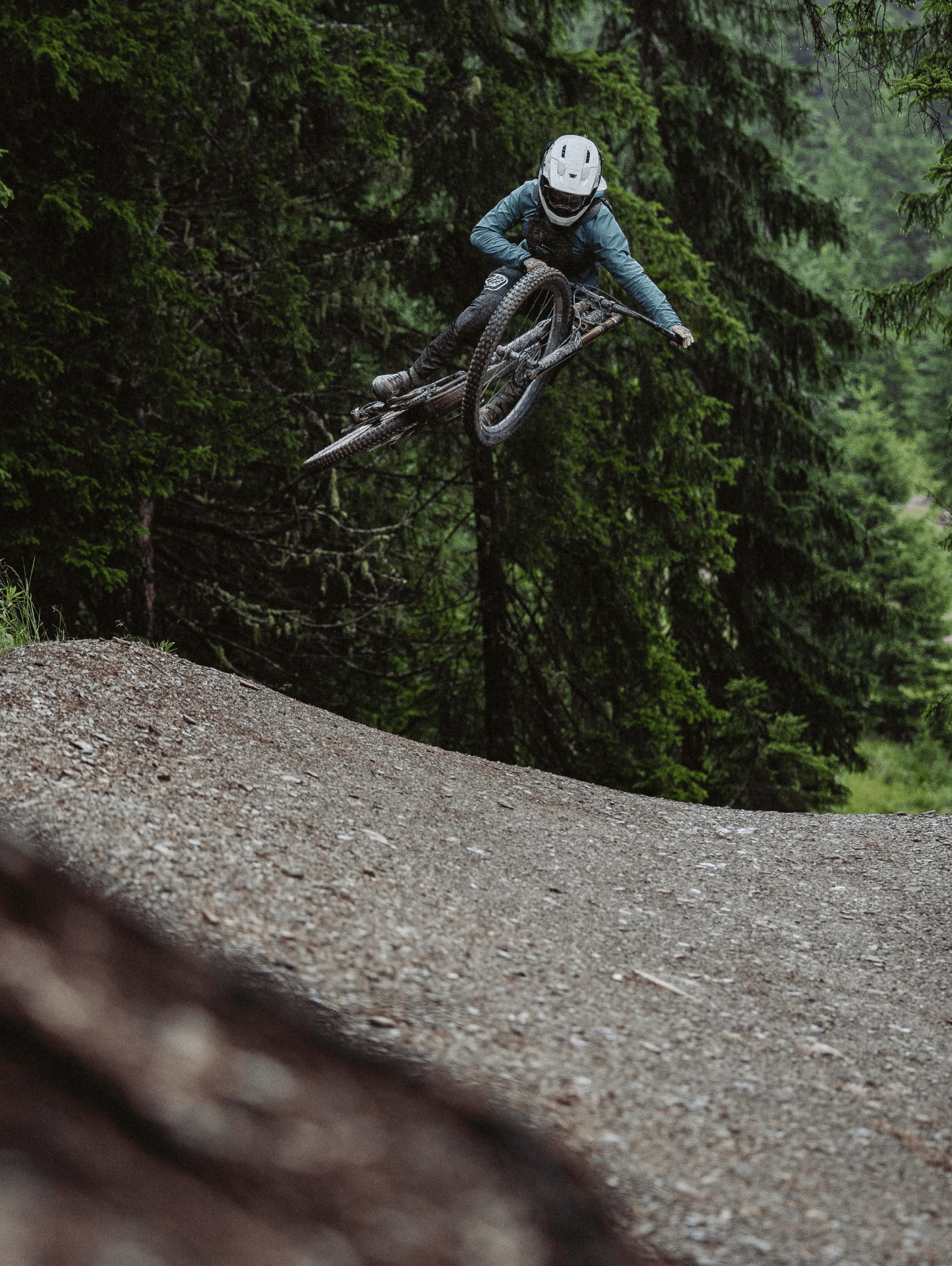 Person auf Mountainbike springt über Rampe im Wald.